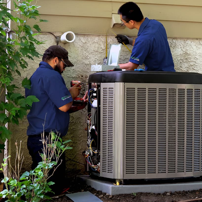 Two Harp HVAC technicians installing a brand-new residential outdoor air conditioning condenser unit during a home AC replacement service.