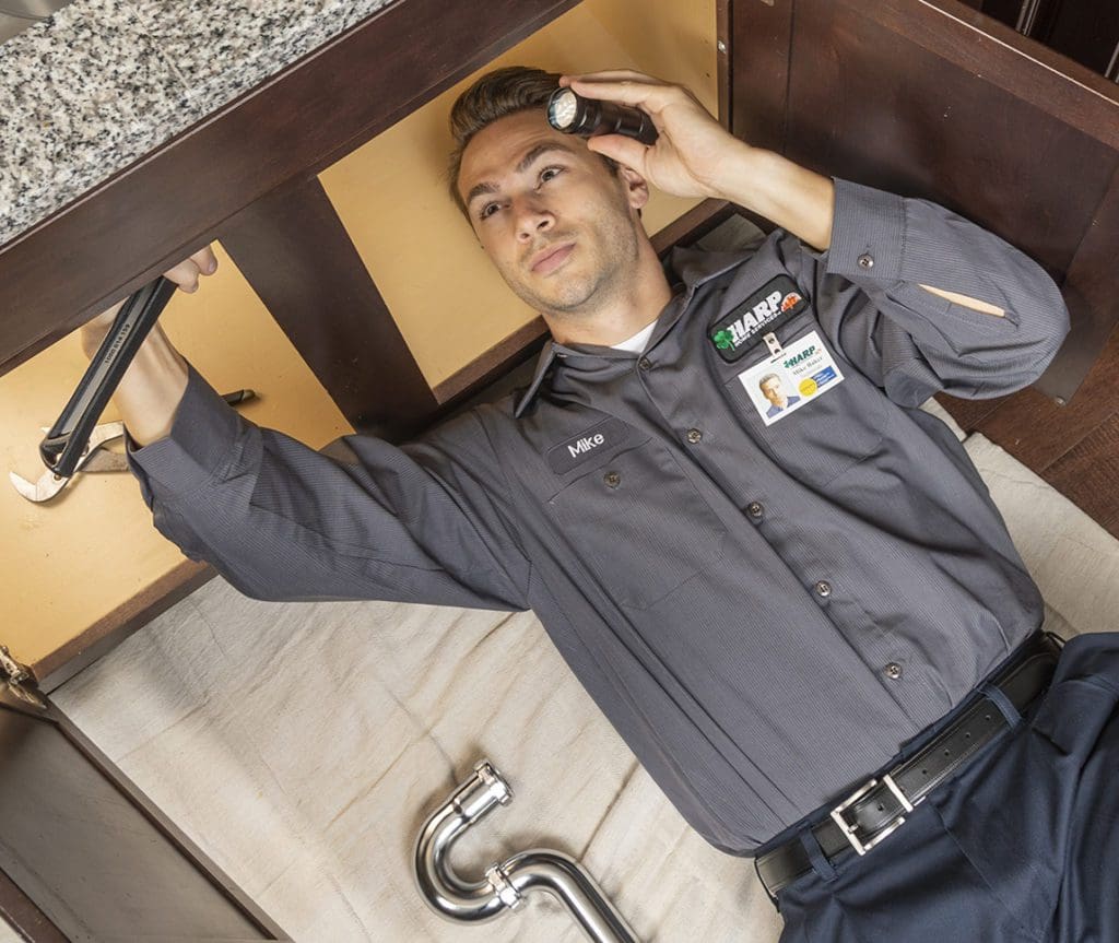 HARP Home Services technician operating plumbing repairs on a kitchen sink